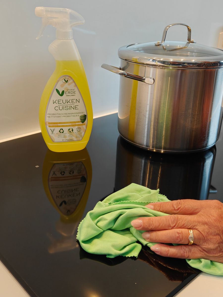 Probiotische keukenspray van Storia Verde naast een kookpot, terwijl een kookplaat wordt schoongemaakt met een groen doekje